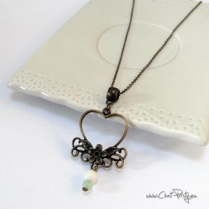 Détail du collier pendentif cœur suspendu à une chaîne fine en bronze