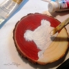 Création artisanale en cours de peinture : ourson blanc sur rondin de bois