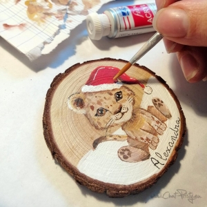 Suspension illustrée personnalisée pour Noël, lionne souriante sur rondin, prénom manuscrit