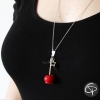 Collier sautoir pomme d'amour rouge porté sur pull noir gros plan bijou pomme d'amour